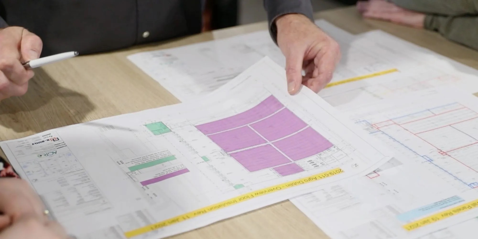 Two people working through a marked-up cold store layout drawing