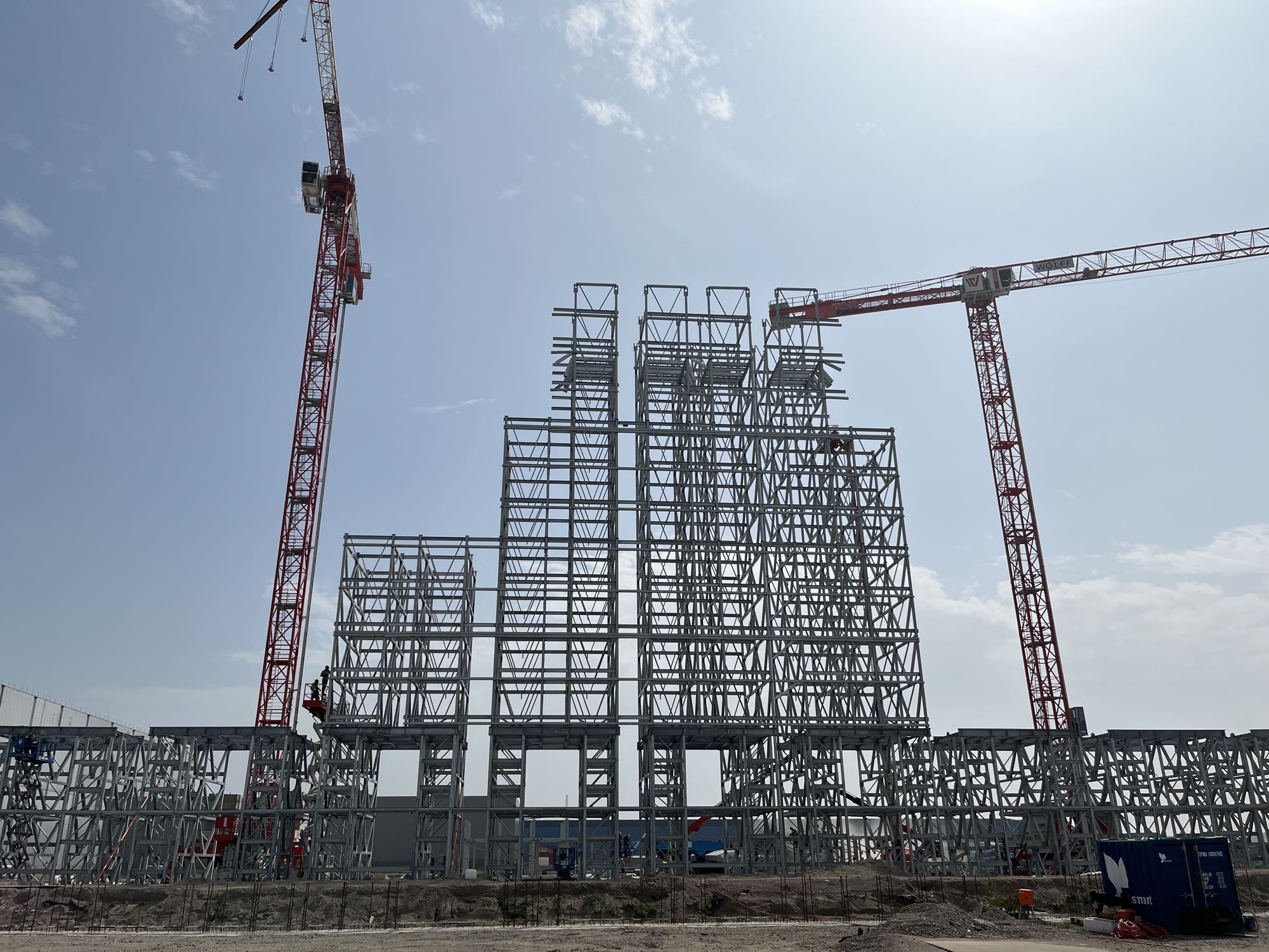 The steel frame of a high-bay cold store going up between two tower cranes
