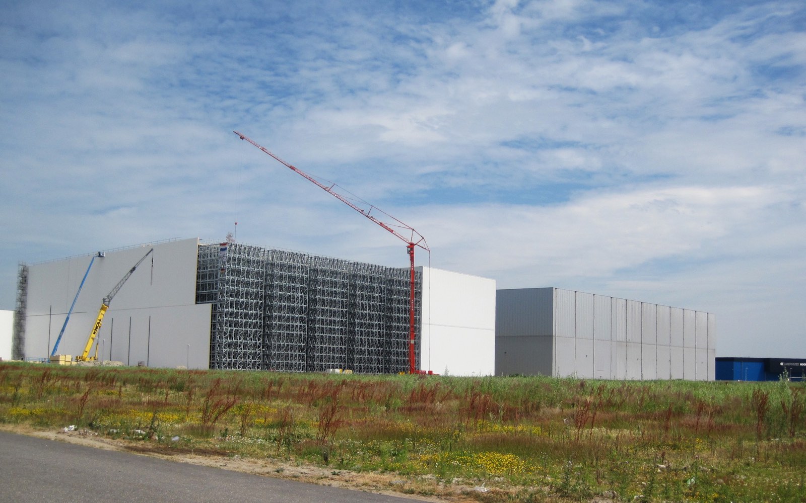 Cold store under construction, the steel frame of its high-bay section standing open beside a tower crane